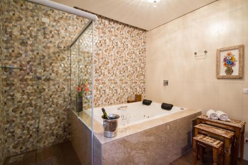y baño con bañera y ducha acristalada. en Pousada Cantinho da Serra, en Campos do Jordão