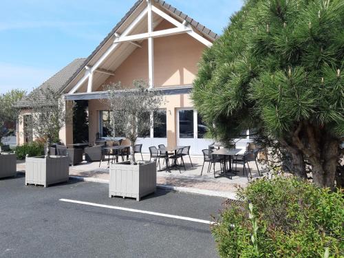 a building with tables and chairs and a tree at Sure Hotel by Best Western Châteauroux in Le Poinçonnet