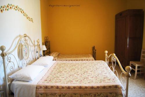 two beds in a bedroom with yellow walls at Agriturismo Signorini in Orciatico
