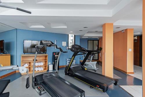 a gym with two tread machines and a flat screen tv at Slaviero Hotel Curitiba Batel in Curitiba