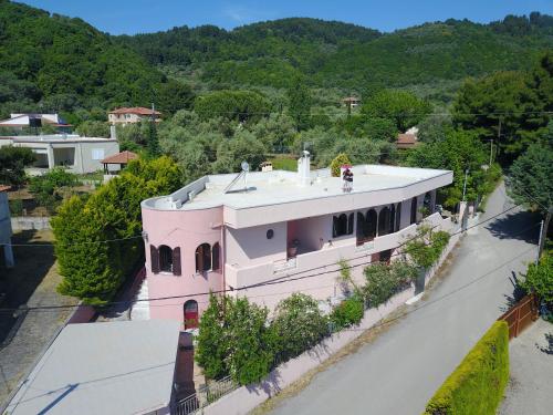 een roze huis met bomen voor een berg bij Villa Ioanneta in Achladi