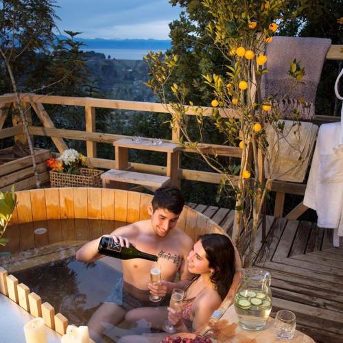 a man and woman in a hot tub with a bottle of wine at Cabañas Tungulú in Puerto Montt