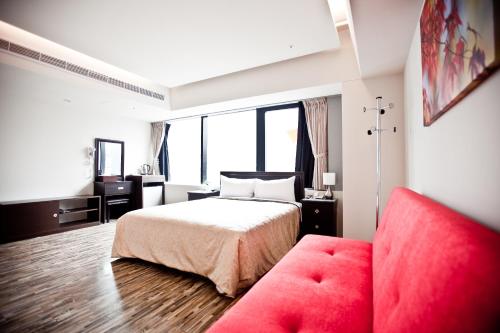 a bedroom with a bed and a red couch at Sodamazon Business Hotel in Zhongli