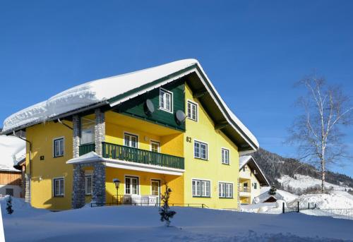 uma casa amarela com neve no telhado em Kukoricza Hacienda em Bad Mitterndorf