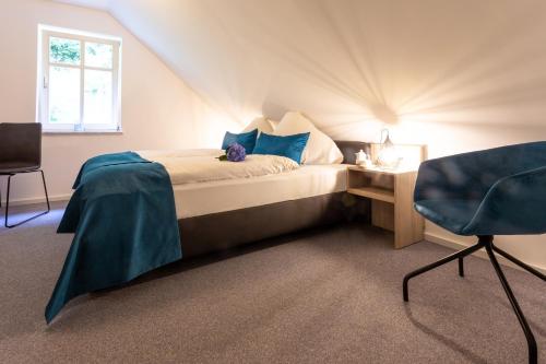 a bedroom with a bed with blue pillows and a chair at Villa Sachsenhof - Pension - Frühstück buchbar - nur 700m vom Gesundheitsbad ACTINON in Bad Schlema