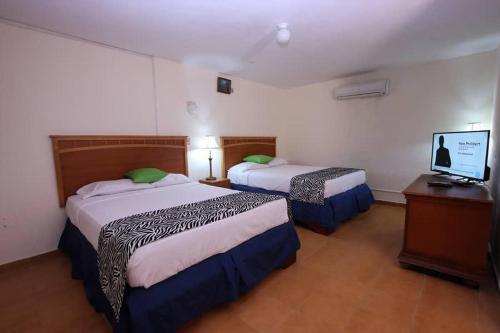 um quarto de hotel com duas camas e uma televisão de ecrã plano em Residence Royale Hôtel em Cabo Haitiano