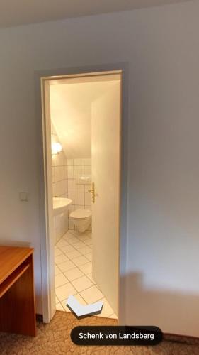 a bathroom with a door open to a toilet at Hotel & Restaurant Schenk von Landsberg in Teupitz