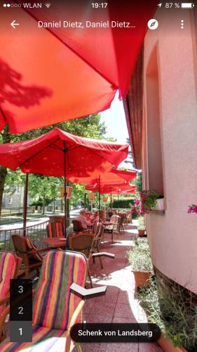 a group of tables and chairs with red umbrellas at Hotel & Restaurant Schenk von Landsberg in Teupitz