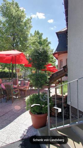 a patio with tables and chairs and red umbrellas at Hotel & Restaurant Schenk von Landsberg in Teupitz