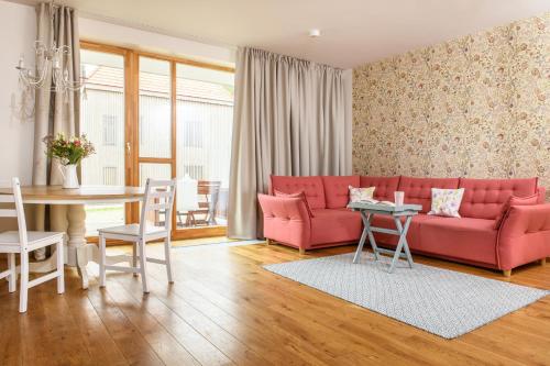 uma sala de estar com um sofá rosa e uma mesa em Kopu Vetrunges - Nida Apartments em Nida