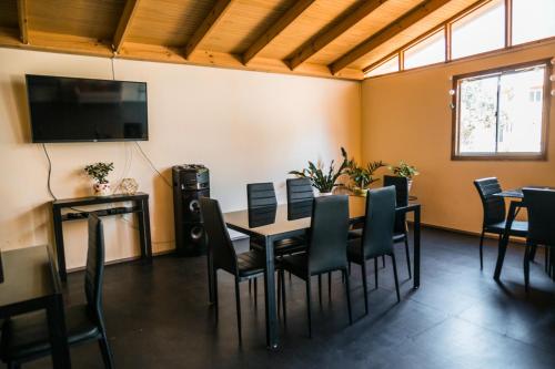 a dining room with a table and chairs and a flat screen tv at Cabañas Maihue in La Serena