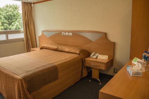 a hotel room with a bed and a telephone at Hotel Milan CDMX in Mexico City