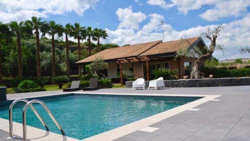una piscina frente a una casa con palmeras en Holiday Homes Borgo Papardo, en Giarre