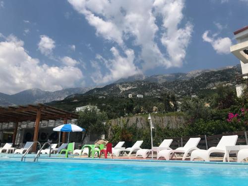 a group of chairs and a swimming pool with mountains at Olives Residence in Dhërmi
