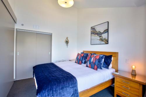 ein Schlafzimmer mit einem Bett und eine Kommode mit einem Schreibtisch in der Unterkunft Supreme Lakefront in Queenstown