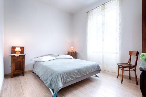 a bedroom with a bed and a chair and a window at Seaview apartment Bambo in Komiža