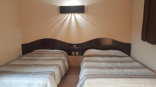 a bedroom with two beds and a light on the wall at Costa Miramar in Acapulco