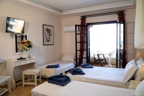 een kamer met 2 bedden en een raam bij Vasilaras Hotel in Skala