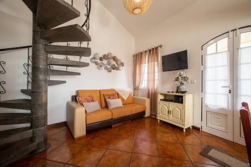 a living room with a couch and a spiral staircase at Casa das Arcadas in Angra do Heroísmo