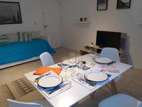 Una mesa blanca con sillas, platos y copas de vino. en Apartamento Benegas, en Mendoza