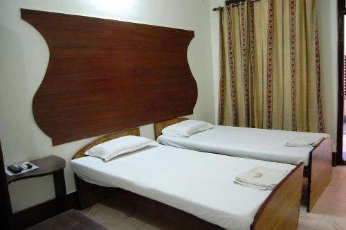two twin beds in a room with a headboard at Sai Palace in Agra