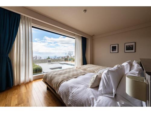 a bedroom with a bed and a large window at the salon 伊豆高原 Hotels & Resort in Ito