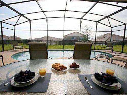 a table with plates of food and drinks and a pool at Windsor Hills Resort 5BR Villa, Amenities, Private Pool & Water Park, Near Disney, Sea World, Universal in Orlando