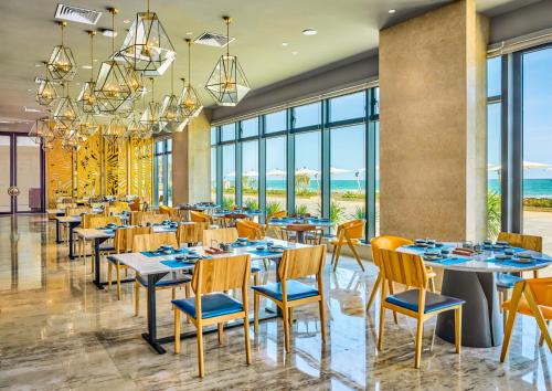 a restaurant with tables and chairs and large windows at Dusit Thani Shuangyue Bay Resort Huizhou in Huidong