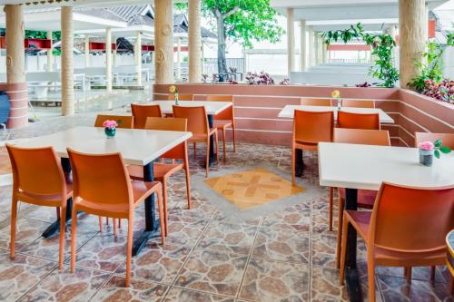 a restaurant with white tables and orange chairs at Cawit Resort and Cafe in Camotes Islands