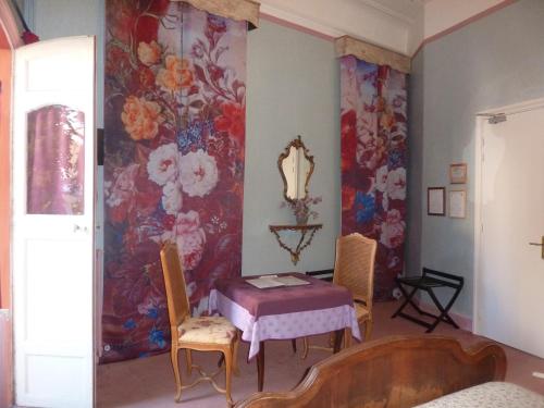a dining room with a table and a floral wallpaper at Hôtel du Fiacre in Carpentras