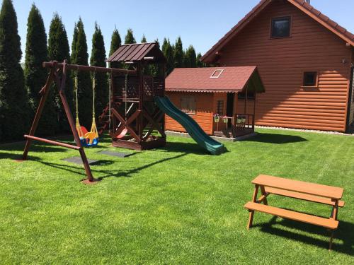 a playground with a slide and a bench in a yard at Domki Wczasowe Papaya in Kołobrzeg
