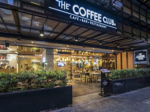 a coffee shop with a cafe with tables and chairs at Maitria Hotel Sukhumvit 18 Bangkok – A Chatrium Collection in Bangkok