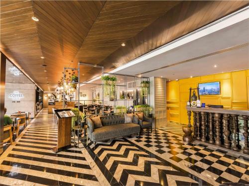a lobby with couches and chairs in a building at Maitria Hotel Sukhumvit 18 Bangkok – A Chatrium Collection in Bangkok
