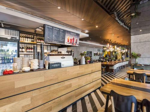 a restaurant with a counter and tables and chairs at Maitria Hotel Sukhumvit 18 Bangkok – A Chatrium Collection in Bangkok