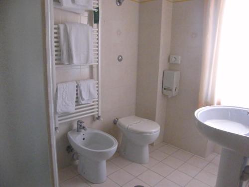 a white bathroom with a toilet and a sink at Hotel Serena in Rieti