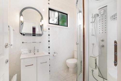 a white bathroom with a toilet and a sink at The Bud House in Rosebud