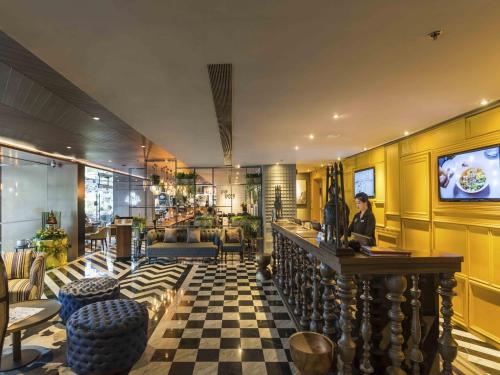 a woman sitting at a bar in a hotel lobby at Maitria Hotel Sukhumvit 18 Bangkok – A Chatrium Collection in Bangkok