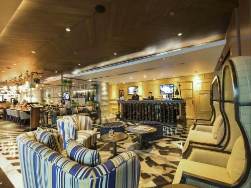 a lobby with couches and tables and a bar at Maitria Hotel Sukhumvit 18 Bangkok – A Chatrium Collection in Bangkok