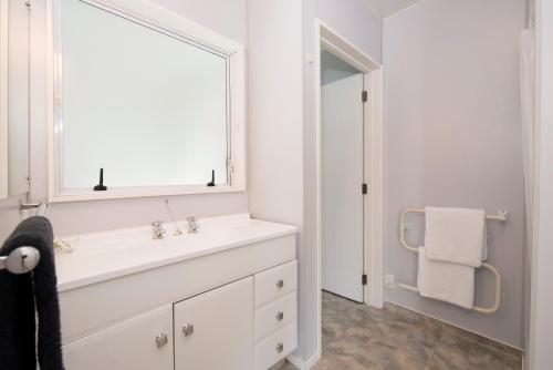a white bathroom with a sink and a mirror at Waimarie on Riverside Motel & Apartments in Nelson