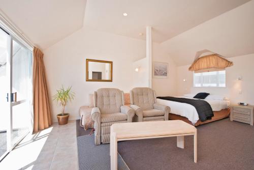 a bedroom with a bed and two chairs at Waimarie on Riverside Motel & Apartments in Nelson