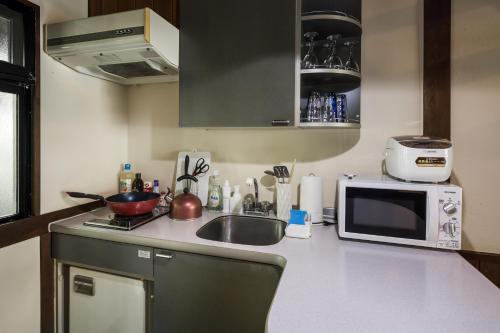 a small kitchen with a sink and a microwave at House-Uma Kensyukan -SEVEN Hotels and Resorts- in Onna