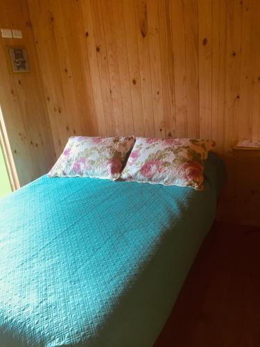 a bed with a blue comforter in a room at Dulac Futrono in Futrono