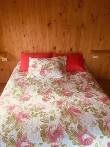 a bed with a floral bedspread and red pillows at Dulac Futrono in Futrono