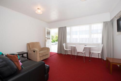 a living room with a couch and a table and chairs at Waimarie on Riverside Motel & Apartments in Nelson