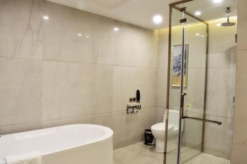 a bathroom with a tub and a toilet and a shower at New Junyue International HotelGuangzhouSouth StationJinlongmetro stationshop in Shunde