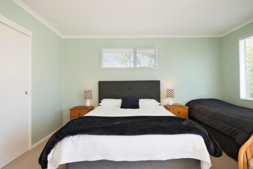 a bedroom with a large bed and two windows at Waimarie on Riverside Motel & Apartments in Nelson