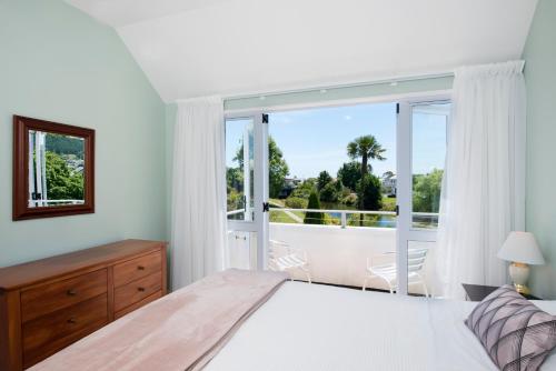 a bedroom with a bed and a large window at Waimarie on Riverside Motel & Apartments in Nelson