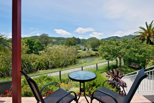 a balcony with chairs and a table and a view of a river at Waimarie on Riverside Motel & Apartments in Nelson