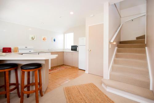 a kitchen with a table and two bar stools at Waimarie on Riverside Motel & Apartments in Nelson