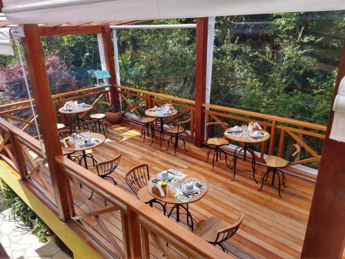 a wooden deck with tables and chairs on it at VELINN Pousadas Flor da Montanha in Monte Verde
